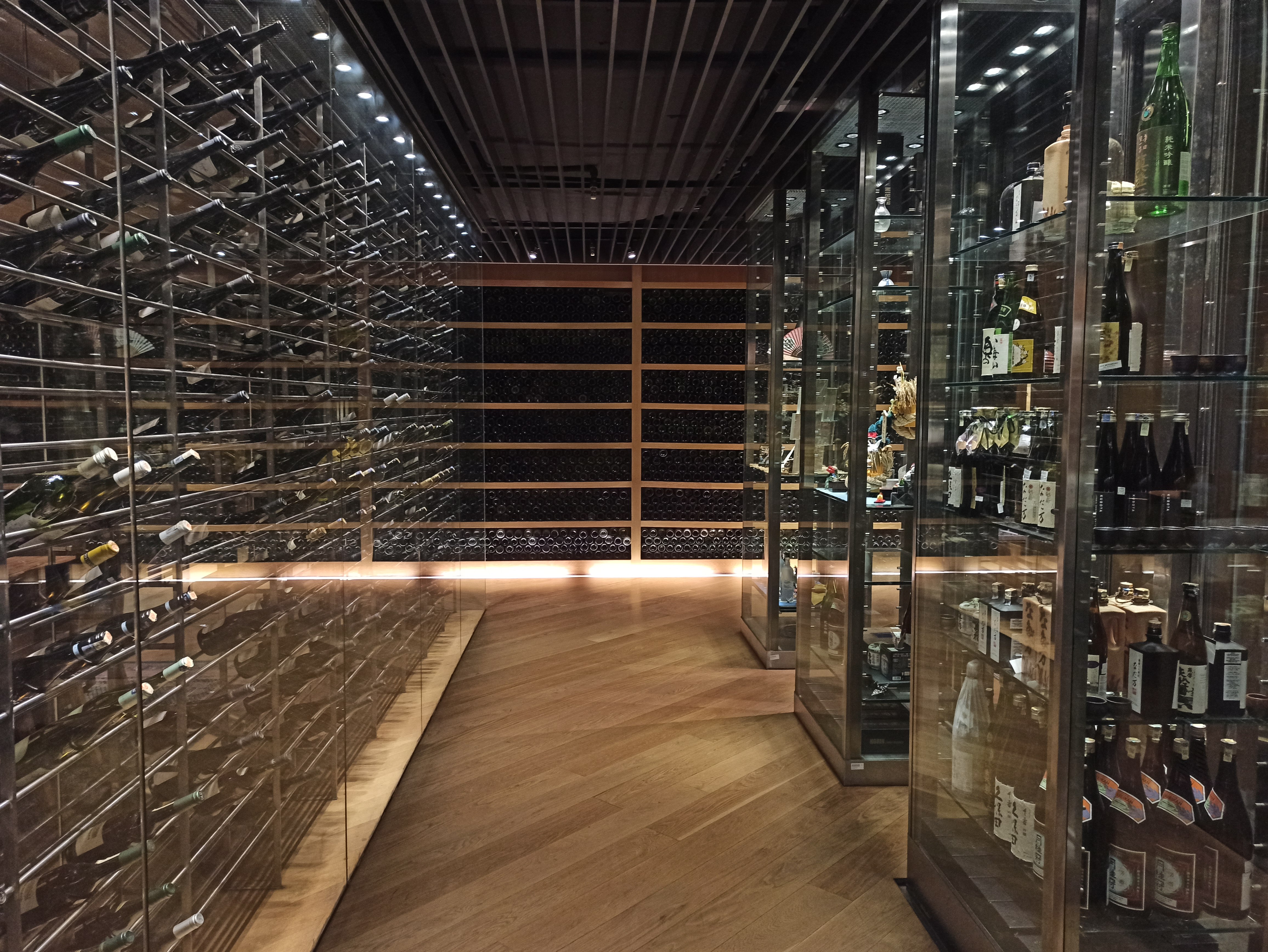 a room with glass shelves and bottles of wine