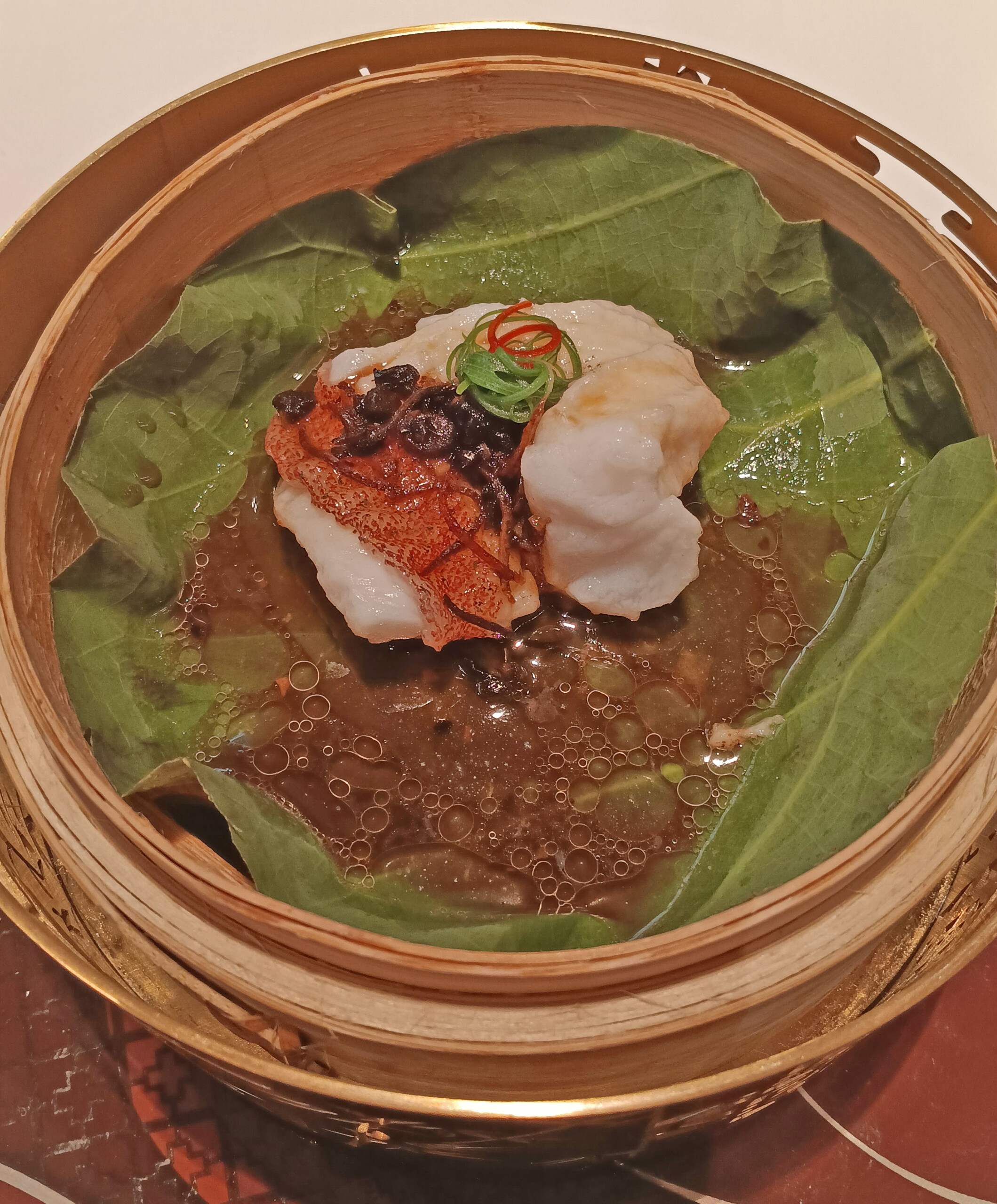Steamed grouper filet with pickled olives served in a lotus leaf