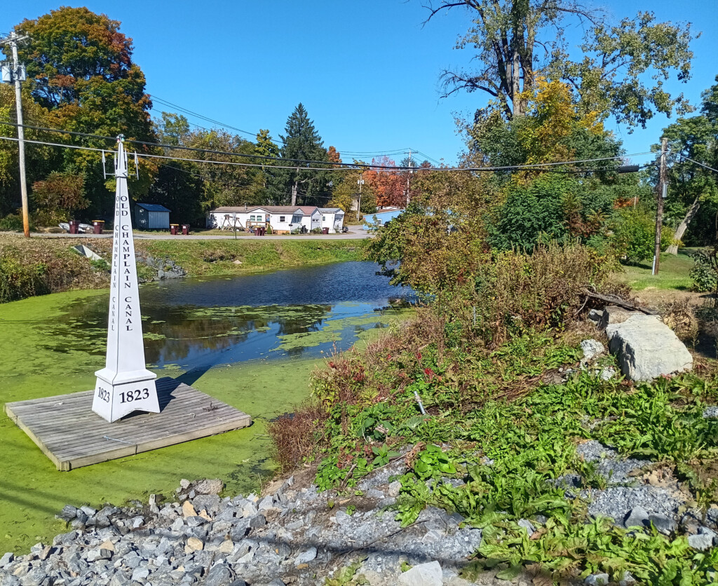 a white tower on a dock next to a pond