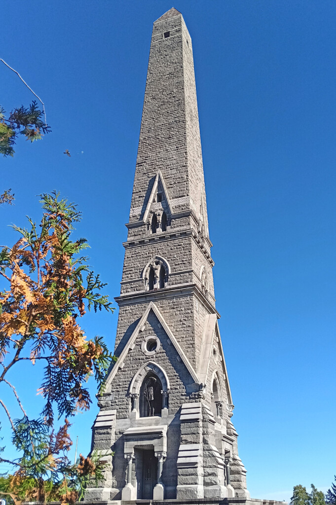 a tall stone tower with a tower and a blue sky