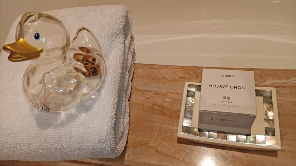 a towel and a glass shoe on a bathtub