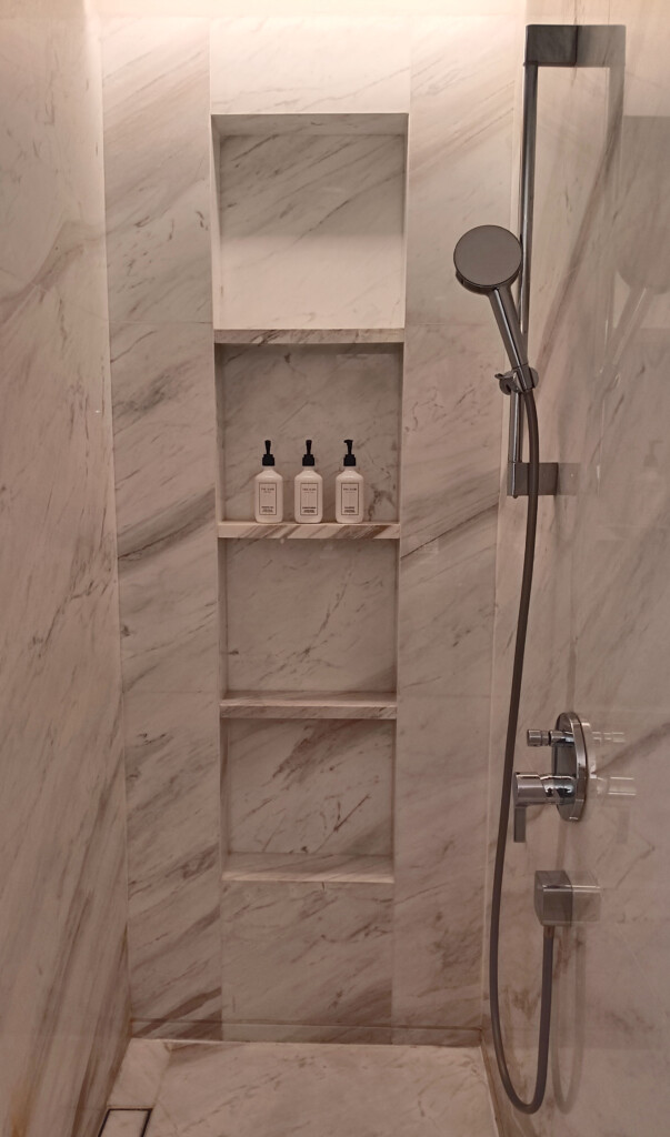 a shower with a shower head and shelves