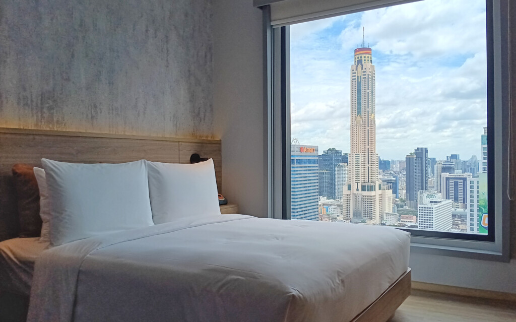 a bed with a large window overlooking a city