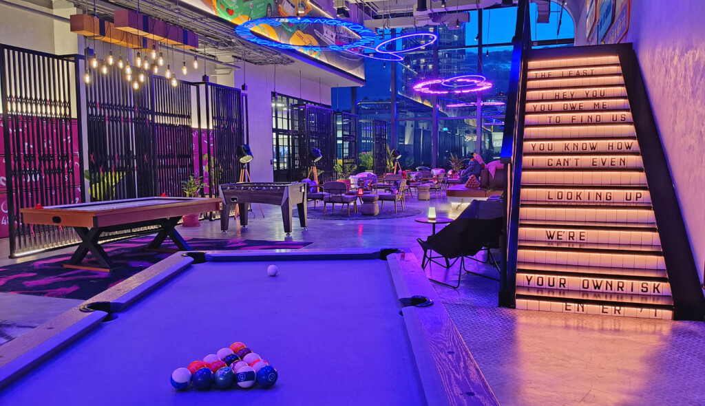 a pool table in a room with a sign and tables and chairs