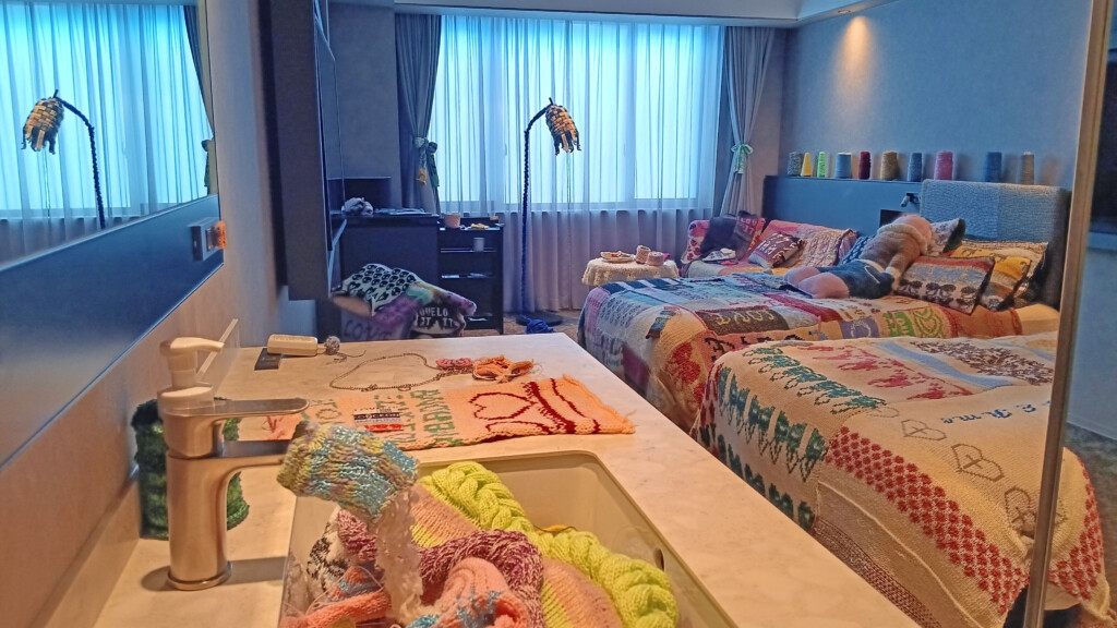 a room with beds and a sink with colorful blankets