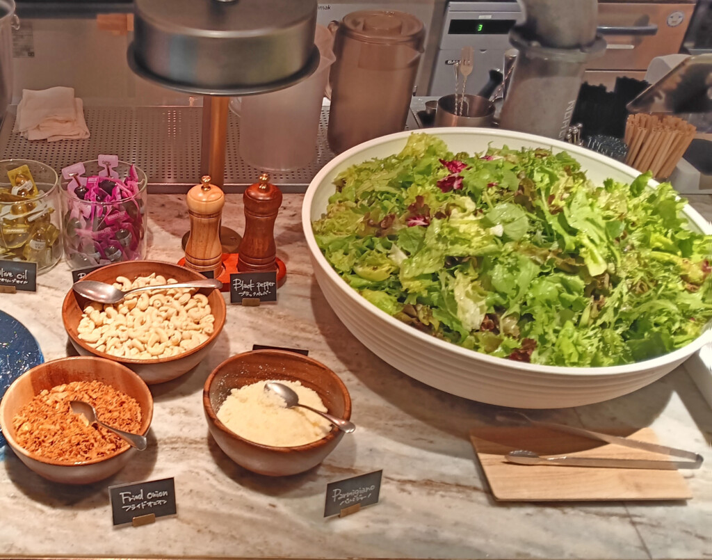 a bowl of salad and bowls of food on a counter