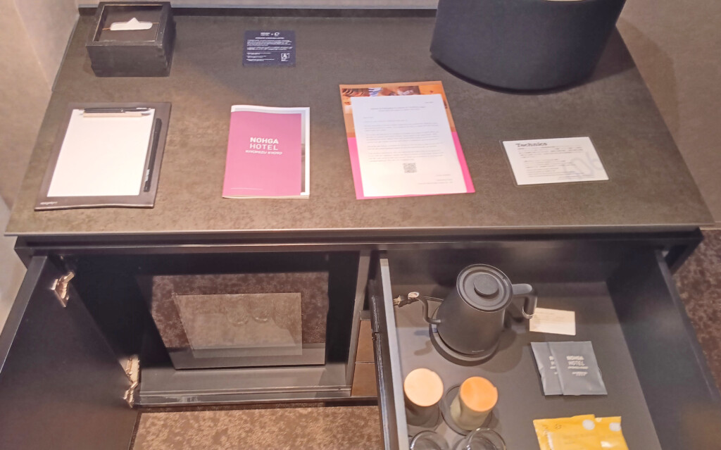 a desk with a drawer full of papers and a coffee pot
