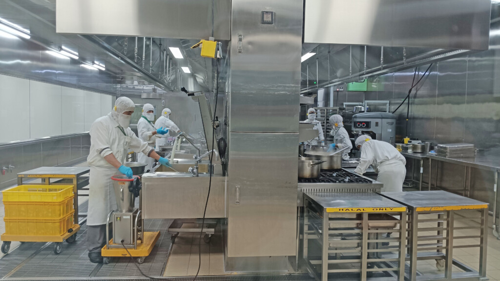 a group of people in white hazmat suits working in a kitchen