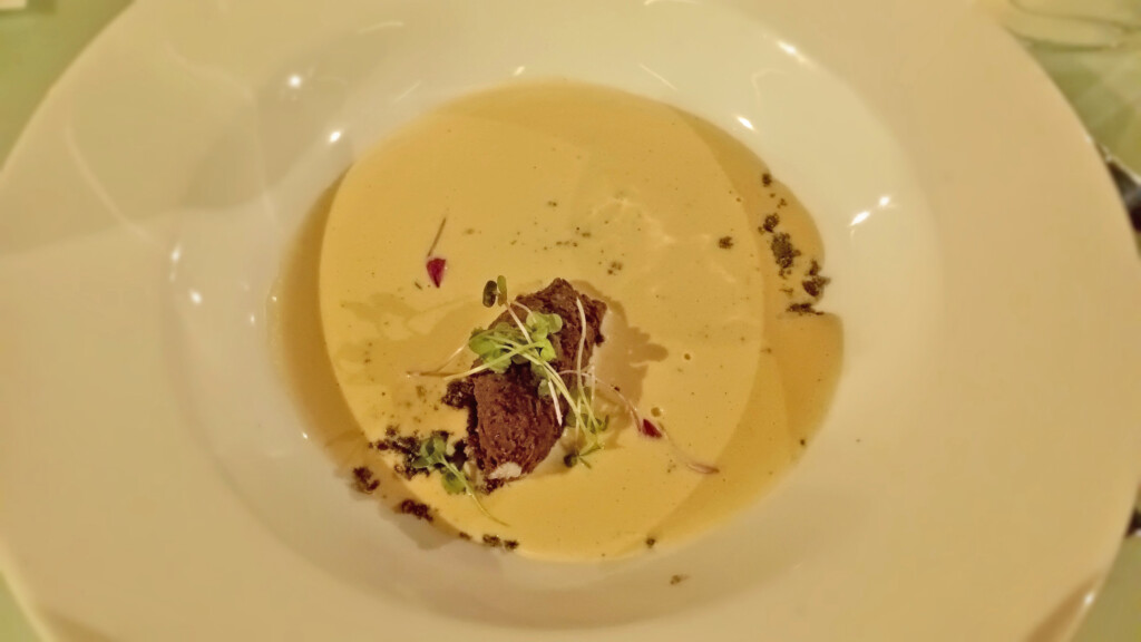 a bowl of soup with brown liquid and sprouts