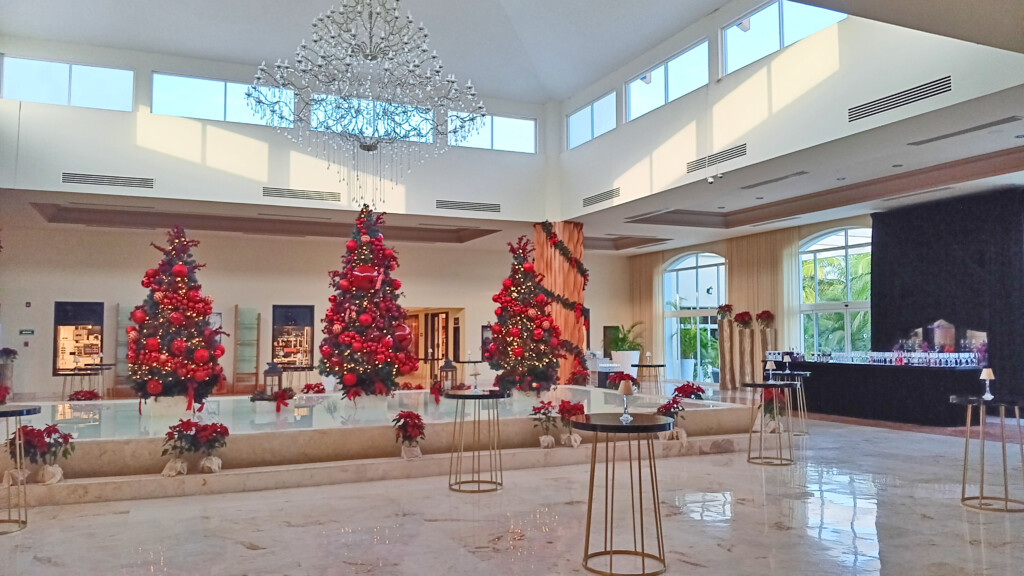 a room with a large chandelier and christmas trees