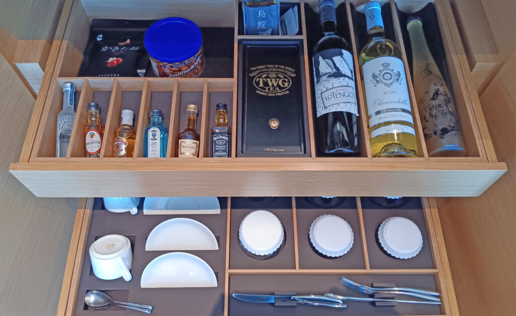 a wooden drawer with bottles and utensils