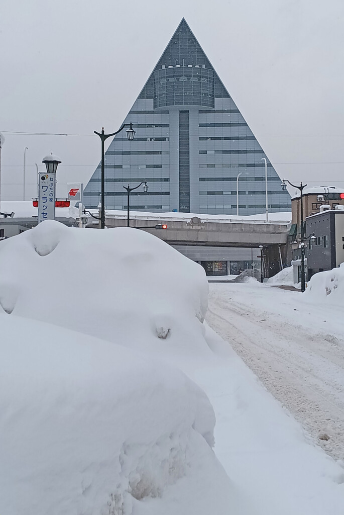 a snow covered street with a pyramid building in the background