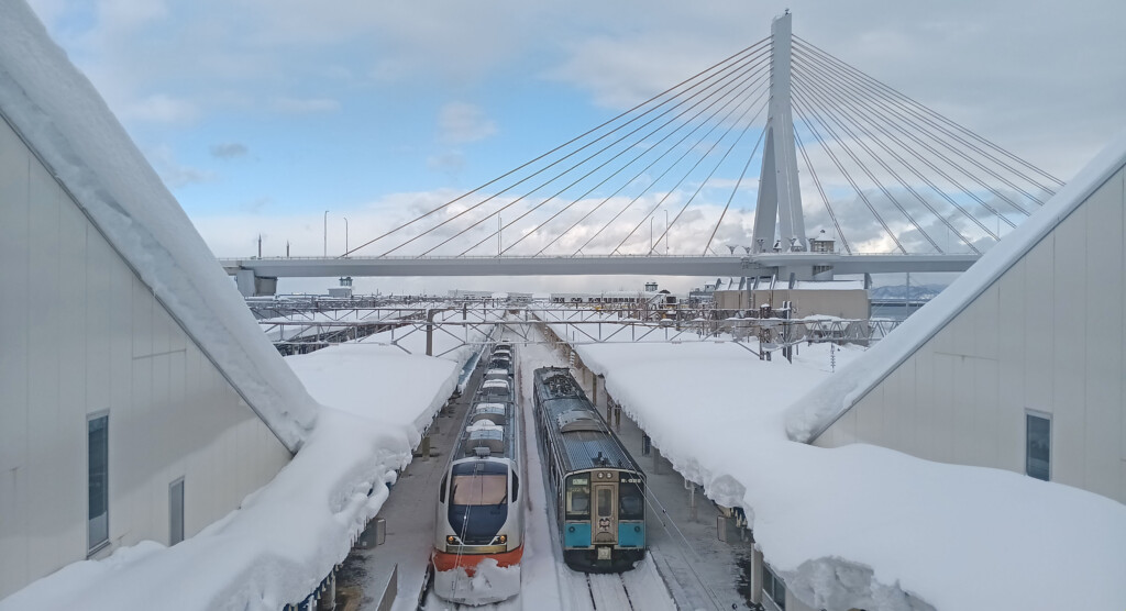 a train station with snow covered roofs and a bridge