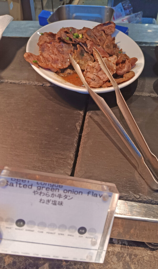 a plate of meat and tongs on a table